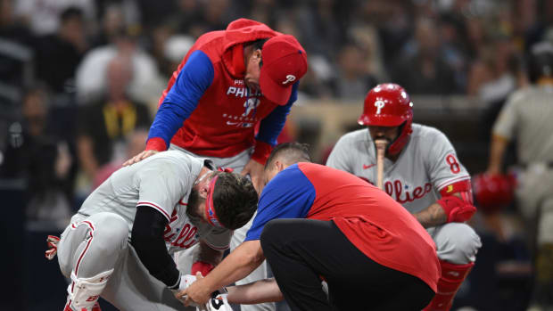 Jun 25, 2022; San Diego, California, USA; Philadelphia Phillies designated hitter Bryce Harper (bottom, left) is checked on by a trainer and interim manager Rob Thomson (top) after being hit by a pitch during the fourth inning against the San Diego Padres at Petco Park. Mandatory Credit: Orlando Ramirez-USA TODAY Sports